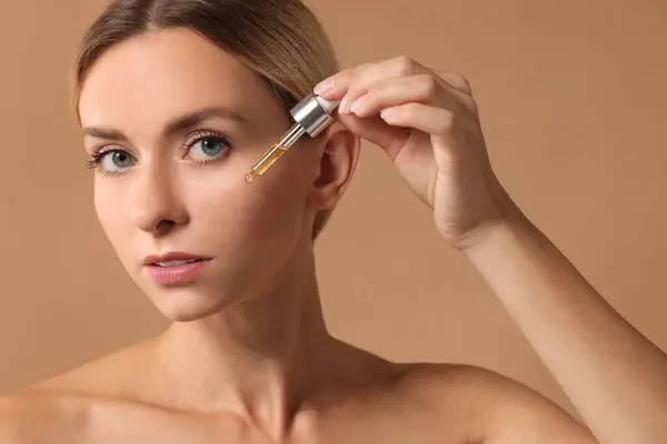 Beautiful Woman Applying Cosmetic Serum Her Face Beige Background Closeup — Stock Photo, Image
