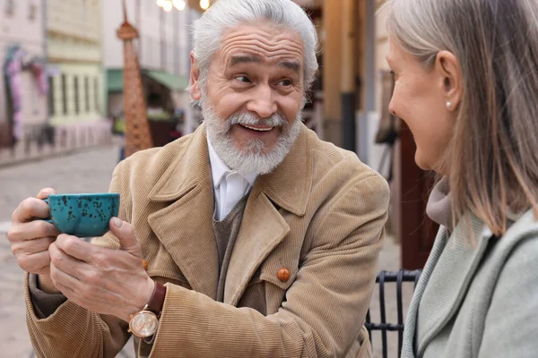 Portrait of affectionate senior couple drinking coffee in outdoor cafe