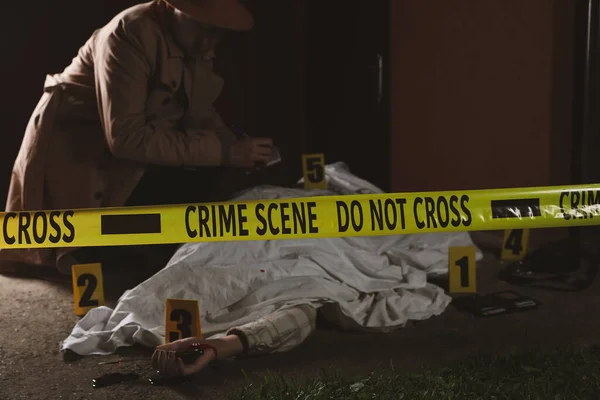调查人员在户外用尸体检查犯罪现场 把重点放在黄色带子上 — 图库照片