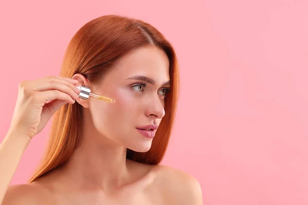 Beautiful Young Woman Applying Cosmetic Serum Her Face Pink Background — Stock Photo, Image