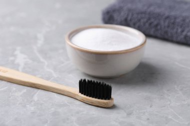 Bambu diş fırçası ve kabartma tozu açık gri masada, yakın plan.