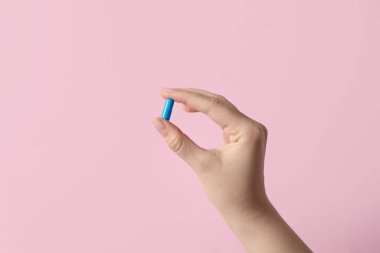 Pembe arka planda hapları tutan kadın, yakın plan.
