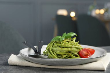 Restoranda gri masada servis edilen ıspanaklı ve domatesli tagliatelle, yakın plan. Makarna yemeğinin enfes sunumu