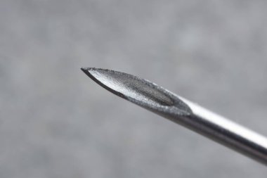 Bulanık gri arka planda tıbbi iğnenin makro fotoğrafı