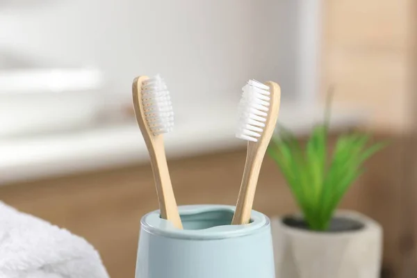 Bamboo toothbrushes in holder on blurred background, closeup