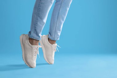 Açık mavi arka planda şık ayakkabılar giyen bir adam, yakın plan. Metin için boşluk