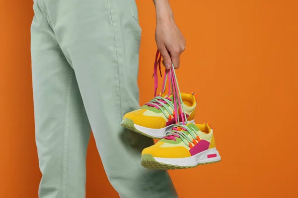 Mujer Sosteniendo Par Elegantes Zapatillas Deporte Colores Sobre Fondo Naranja — Foto de Stock