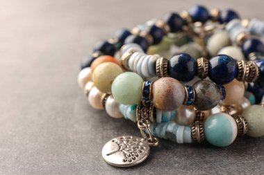 Gri arka planda değerli taşları olan güzel bilezikler, yakın plan. Metin için boşluk