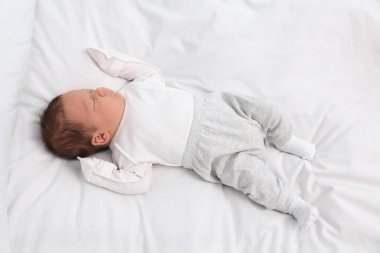 Sevimli yeni doğmuş bebek beyaz yumuşak bir yatakta uyuyor.