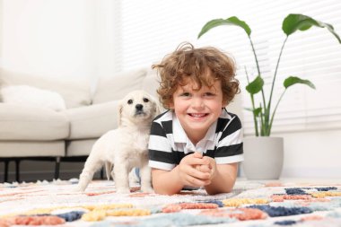 Evdeki halıda sevimli köpek yavrusu olan küçük çocuk.