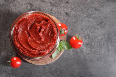 Lezzetli domates ezmesi kavanozu ve gri desenli masa üzerindeki malzemeler düz. Metin için boşluk