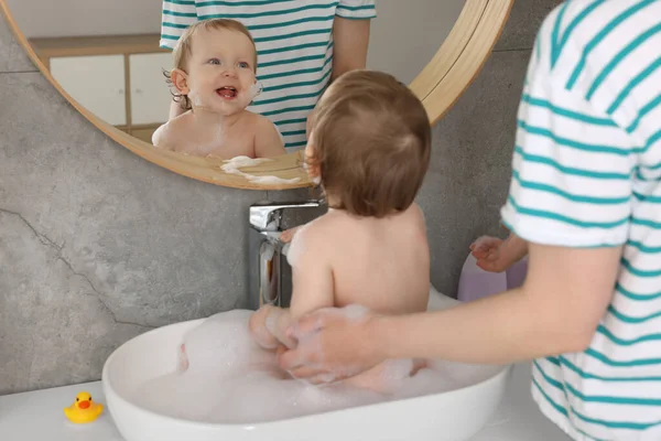 Äiti Pesee Pienen Vauvansa Pesualtaassa Kotona — kuvapankkivalokuva