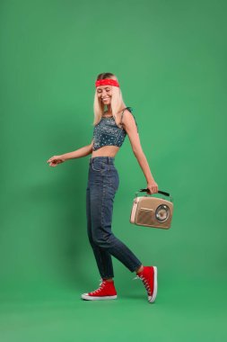 Yeşil arka planda retro radyo alıcısı olan mutlu hippi kadın.