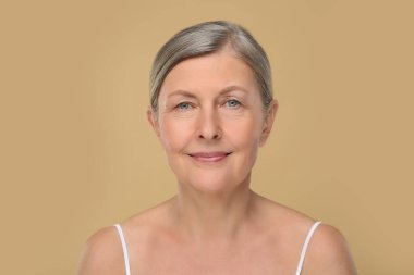 Bej arka planda yaşlanmakta olan yaşlı bir kadının portresi. Yenilenme tedavisi