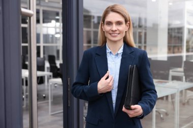 Ofis yakınlarında deri portföyü olan kadın emlakçı.