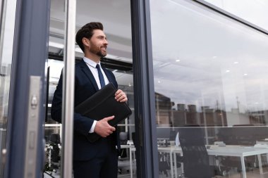 Ofis dışında deri portföyü olan erkek emlakçı.