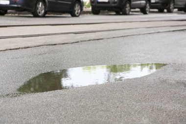Yolun kenarındaki su birikintisinin manzarası. Yağmurlu gün