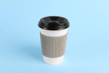 Açık mavi arka planda plastik kapaklı kağıt bardak. Kahve hazır.