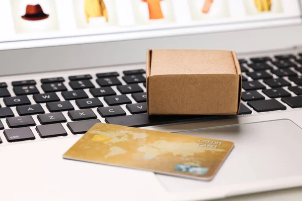 Mini box and credit card on laptop, closeup. Online store