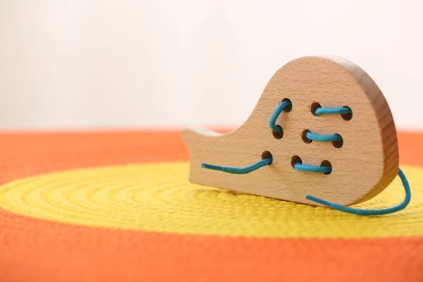 Motor skills development. Wooden lacing toy on color mat, closeup. Space for text