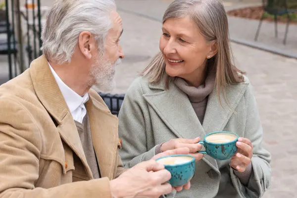 Portrait of affectionate senior couple drinking coffee in outdoor cafe
