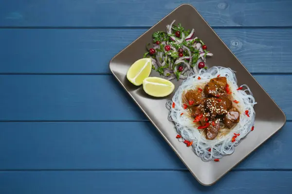 Soya soslu tavuk parçaları, erişte, salata ve limon mavi ahşap masa, üst manzara. Metin için boşluk