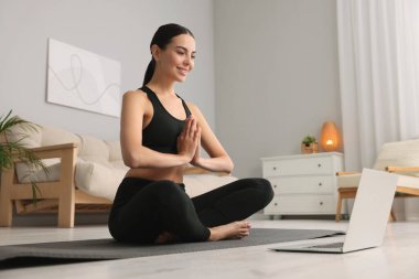 Evdeki yoga minderinde Padmasana egzersizi yapan güzel bir genç kadın. Düşük açılı bir manzara. Lotus pozu