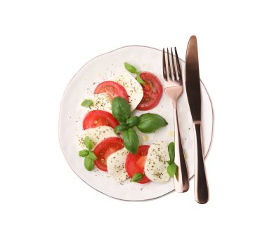 Domatesli, mozzarella, fesleğen, baharat ve çatal bıçaklı bir tabak lezzetli Caprese salatası.