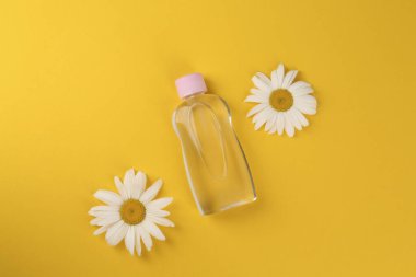 Bebek yağı şişesi ve turuncu arka planda papatyalar.