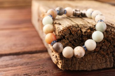 Masanın üzerinde değerli taşlar ve dekoratif ahşap parçaları olan güzel bir bilezik, yakın plan. Metin için boşluk