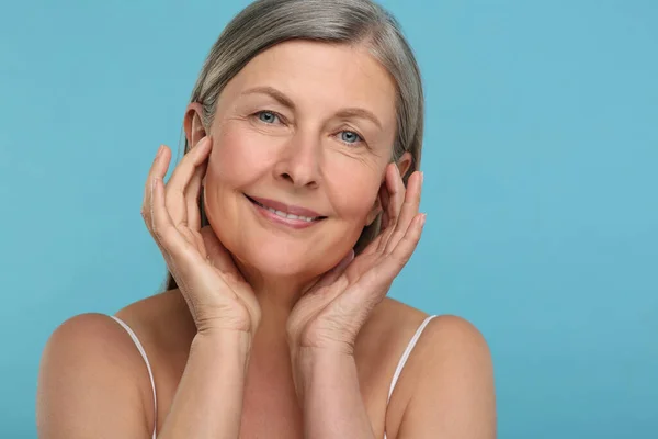 Portrait of senior woman with aging skin on light blue background. Rejuvenation treatment