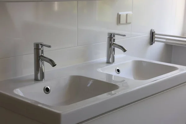 White clean sinks with water taps in bathroom