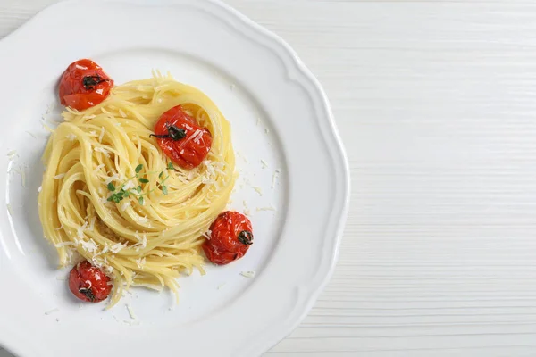 Tasty capellini with tomatoes and cheese on white wooden table, top view and space for text. Exquisite presentation of pasta dish