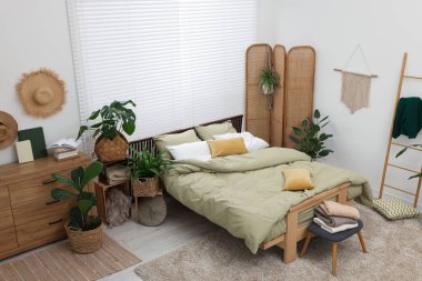 Rahat yatağı olan şık bir yatak odası ve manzaranın üstünde güzel yeşil bitkiler. İç tasarım