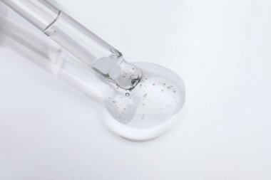 Pipetten ışık yüzeyine kozmetik yağ damlatıyor, yakın plan.