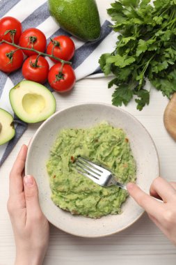 Beyaz ahşap masada nefis guacamole hazırlayan bir kadın.