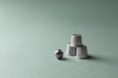 Metal yüksükler ve top soluk zeytin arka planda, yazı için boşluk. Thimblerig oyunu