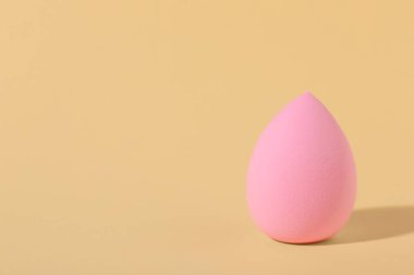 Bej arkaplanda pembe makyaj süngeri, metin için boşluk