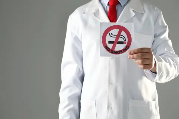 医生持卡没有吸烟标志灰色背景 特写镜头 案文的篇幅 — 图库照片