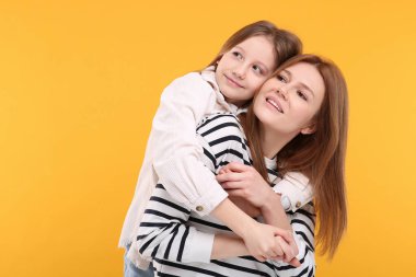 Turuncu arka planda mutlu anne ve tatlı kızının portresi. Metin için boşluk