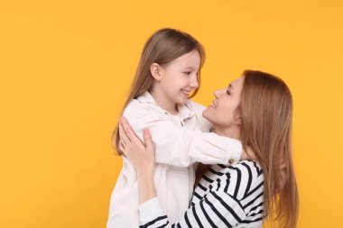 Turuncu arka planda mutlu anne ve tatlı kızının portresi. Metin için boşluk