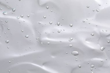 Açık gri arka planda şeffaf temizleme jeli, üst manzara. Kozmetik ürünü