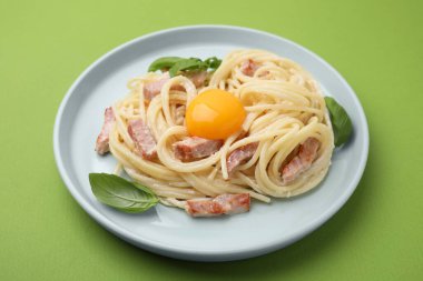 Açık yeşil arka planda yumurta sarısı olan lezzetli Carbonara makarnası, yakın plan.