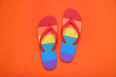 Turuncu arka planda gökkuşağı terlikleri, düz yatış. LGBT gururu