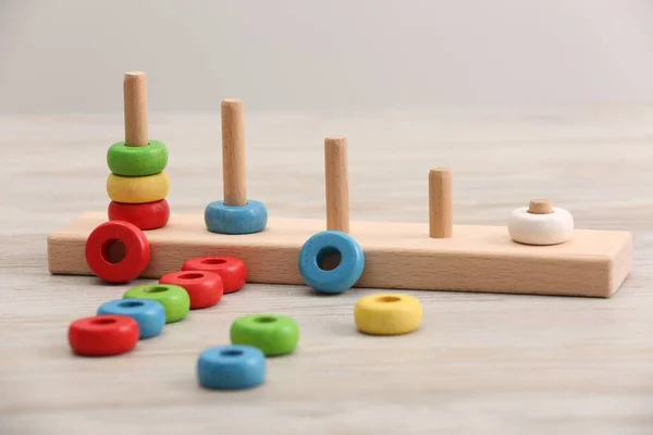 Educational toy for motor skills development. Stacking and counting game pieces on light wooden table
