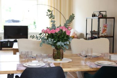 Yemek odasında buketi olan güzel bir masa. Vazoda gül ve okaliptüs dalları