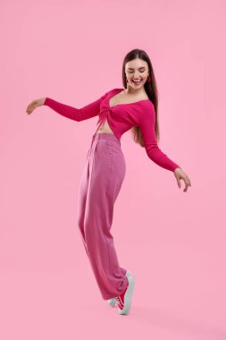 Pembe elbiseli güzel bir kadın dans ediyor arka planda
