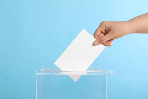 女性把选票放在浅蓝色背景的投票箱里 — 图库照片