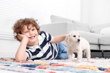 Evdeki halıda sevimli köpek yavrusu olan küçük çocuk.