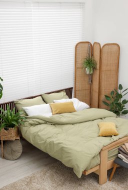 Rahat bir yatak ve yatak odasında güzel yeşil bitkiler.